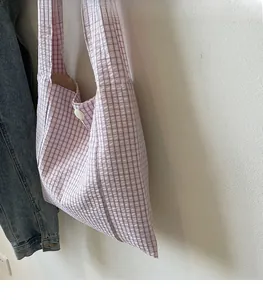 Detailed texture of pink and white checkered canvas tote bag with white round button accent