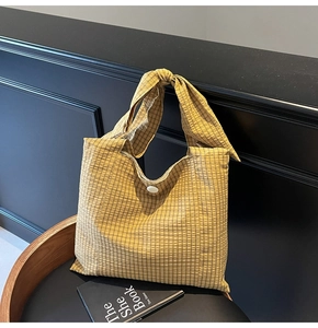 Detail of checkered tote bag in mustard yellow with a unique knotted handle and button closure