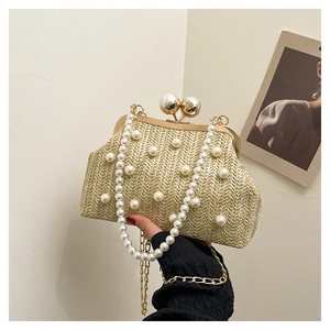 Detail of woven straw handbag with faux pearl accents and elegant gold metal frame clasp