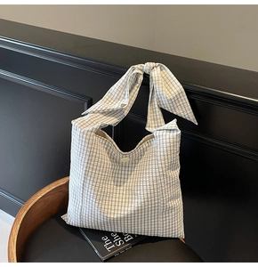 Close-up of black and white checkered tote bag with a unique bow-knot wide handle design