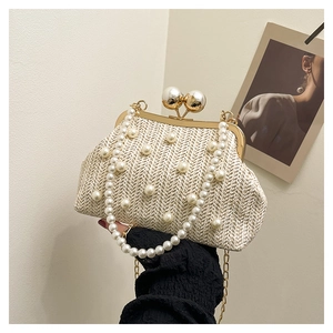 Detail of elegant pearl-embellished straw handbag with gold hardware and beaded handle