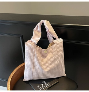 Detail of pink plaid seersucker tote bag with knotted handle on a black leather chair