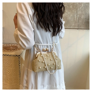 Detail of straw woven bucket bag with pearl embellishments and a gold metal chain strap