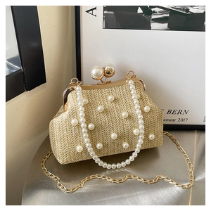 Detailed view of beige straw clutch bag with large pearl accents and gold metal chain