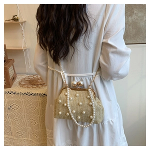 Detail of woven straw pearl clutch bag with gold chain strap on white dress