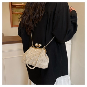 Detailed shot of a beige woven evening bag with pearl embellishments and a gold chain strap