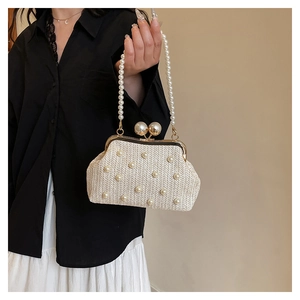 Detail of a beige woven handbag with pearl accents and a beaded handle on a model