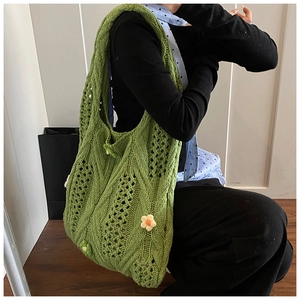 Detail of green knit hobo bag with hollow weave and floral 3D crochet accents