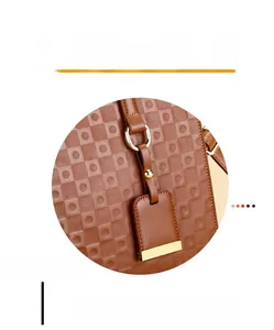 Close-up of brown embossed tote bag showing golden metal rings and reinforced stitching