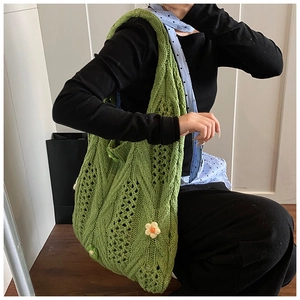 Detail view of grass green woven tote bag with 3D crochet yellow flowers and hollow pattern