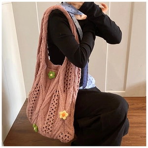 Detail of pink hand-knitted tote bag with floral accents and hollow woven texture