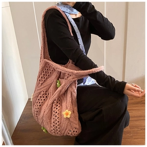 Close-up of pink handmade woven crochet handbag with 3D daisy flowers and hollow-out pattern