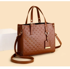 Detail of brown quilted leather tote bag with gold-tone hardware and adjustable strap
