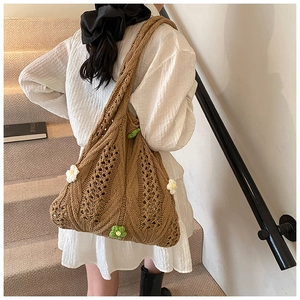 Detail of hand-crocheted brown tote bag with 3D daisy flower accents and woven strap