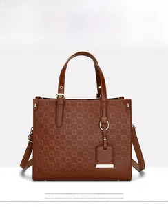 Detail of brown embossed tote bag featuring checkered texture and gold metal hardware