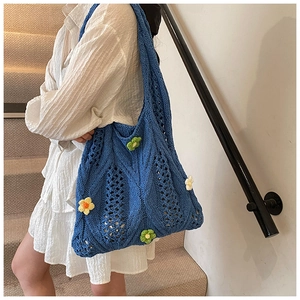 Detail of blue crochet hobo bag with colorful floral embroidery and hollow weave