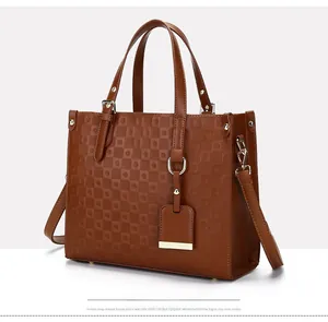 Detail of brown leather tote bag with embossed checkered pattern and gold hardware