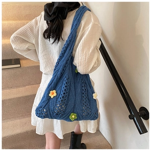 Close-up of royal blue hand-knitted tote bag featuring colorful 3D floral accents