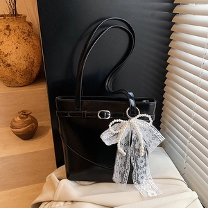 Minimalist black tote bucket bag with lace pearl bow charm in a stylish setting