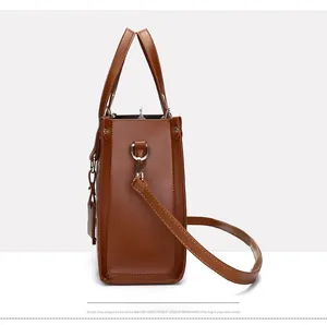 Side view of structured brown tote bag featuring detachable shoulder strap and D-ring hooks
