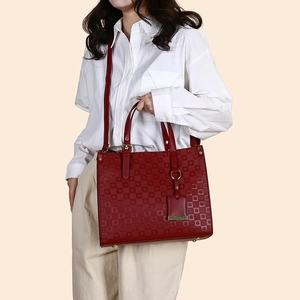 Close-up of red quilted tote bag with golden hardware and protective metal feet