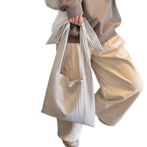 Checkered black and white tote bag with bow knot handles and single button closure