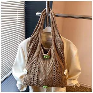Detail of a brown woven knit tote bag with delicate white and green floral decorations