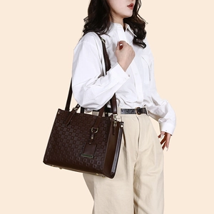 Deep brown quilted tote bag shown on shoulder of model in white shirt and beige pants