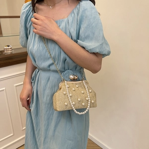 Beige woven pearl evening handbag with gold chain strap shown on a blue dress model