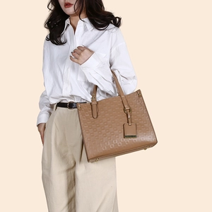 Close-up of embossed geometric texture and dual handles on a brown tote handbag