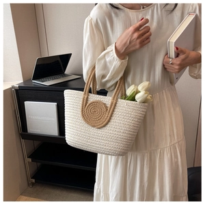 Detail of hand-woven beige tote bag with brown circular accents held by a woman