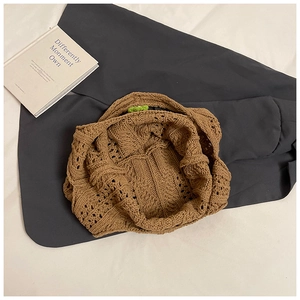 Macro detail of brown woven knit handbag showing hollow pattern and green accents