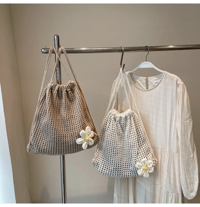 Detail of woven straw backpacks featuring hollow knit flower patterns and drawstring closure