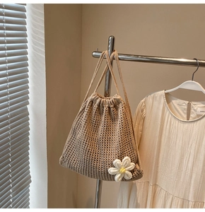 Close-up of beige crochet drawstring bag featuring a 3D knit daisy flower detail