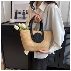 Detail of woven straw tote bag with black circular accents and matching handles