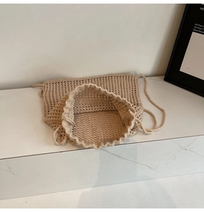 Close-up of beige hollow woven shoulder bag with drawstring closure and texture