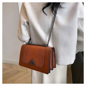 Détail du sac bandoulière marron gaufré crocodile avec chaîne et fermoir en métal