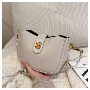Detailansicht der cremefarbenen Eimertasche mit goldenem Verschluss und weichem Leder