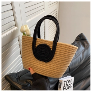 Detail of woven straw tote bag with unique black spiral handles and interior flower decoration