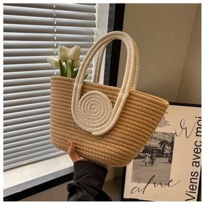Detail of woven straw tote bag featuring white spiral patterns and tulip decorations