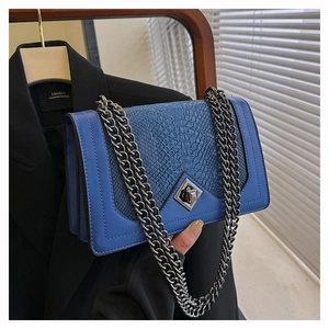 Détail du sac à main bleu foncé avec motif crocodile et bandoulière en chaîne