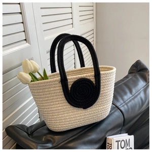 Close-up of woven tote bag featuring black spiral handle detail and white tulip decor