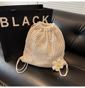 Detail of cream woven crochet bag with handmade daisy flower and drawstring closure