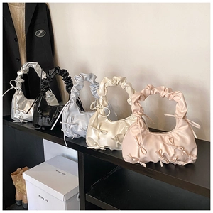 Detail view of five assorted colorful bow shoulder bags with ruched handles on display