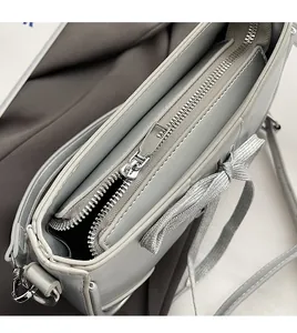 Detailansicht des glatten Silber-Reißverschlusses und der Schleife auf der grauen Tasche