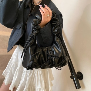 Detail shot of black pleated cloud bag featuring delicate handcrafted ribbon bow accents