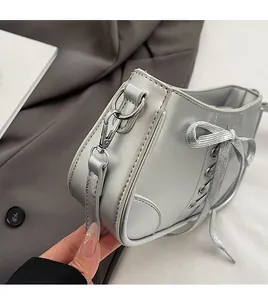 Detail der silbernen Tasche in Stiefelform mit abnehmbaren Haken und Schnürsenkel-Dekor