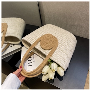 Detail of woven tote bags with gold thread accents and decorative round handle grips