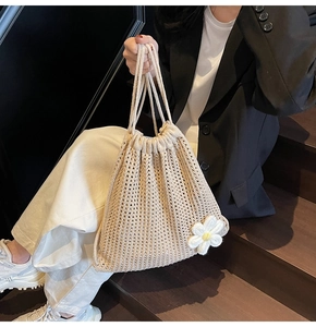 Close-up of beige crochet drawstring bag with a daisy flower on a woven hollow structure
