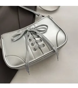 Detail der silbernen Metallic-Umhängetasche mit modischem Kreuzschnürungs-Schleifen-Design